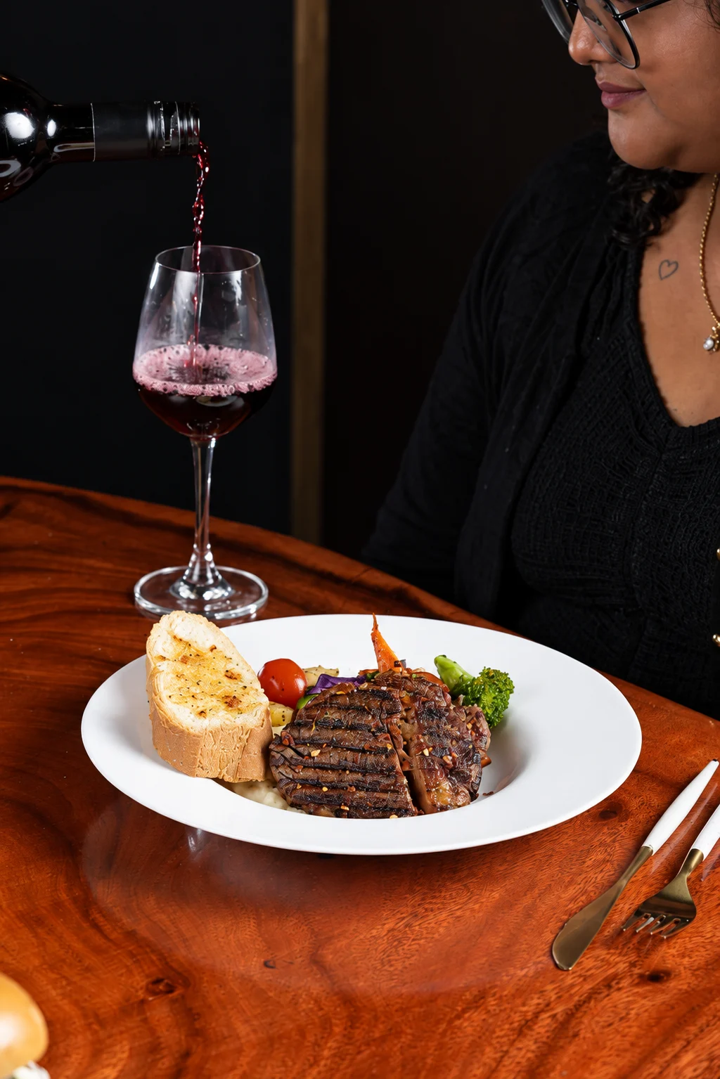 Wine being poured beside a Ninan's steak