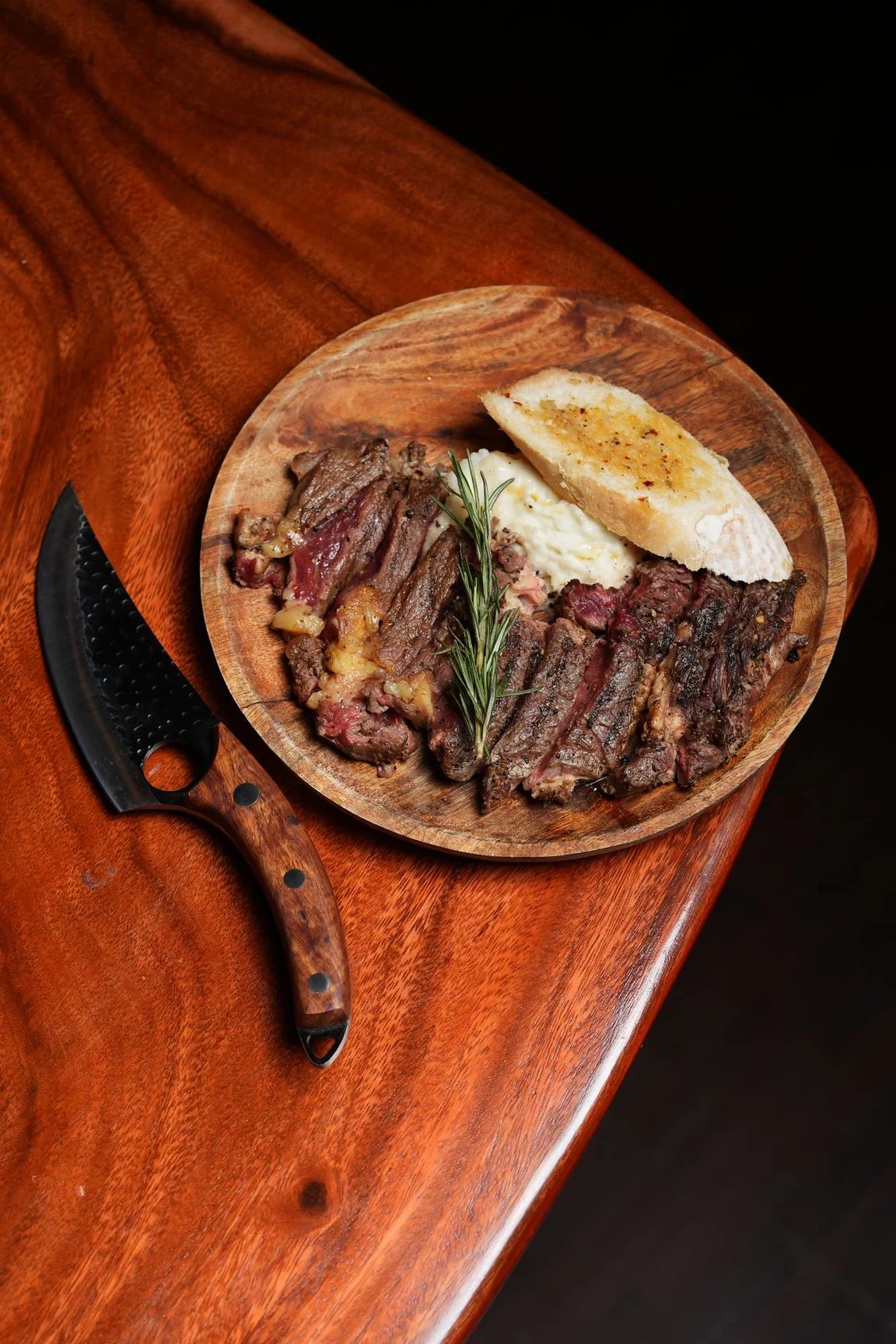 Ninan's Kinky Ribeye Steak sliced on a wooden plate